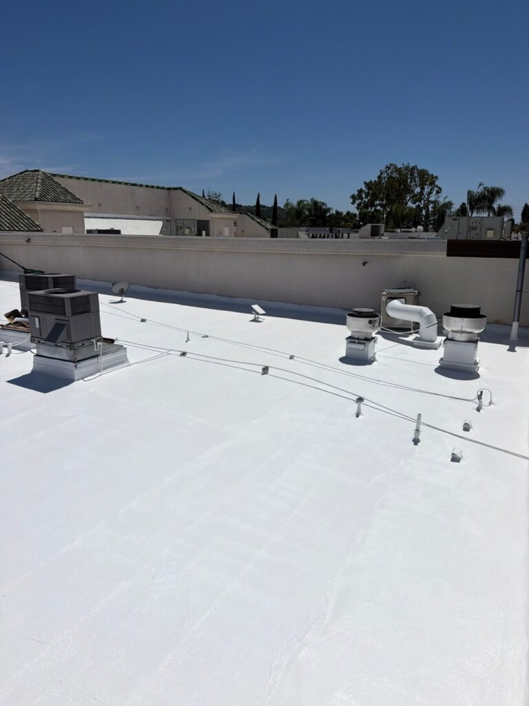 White commercial rooftop with HVAC units under clear sky.