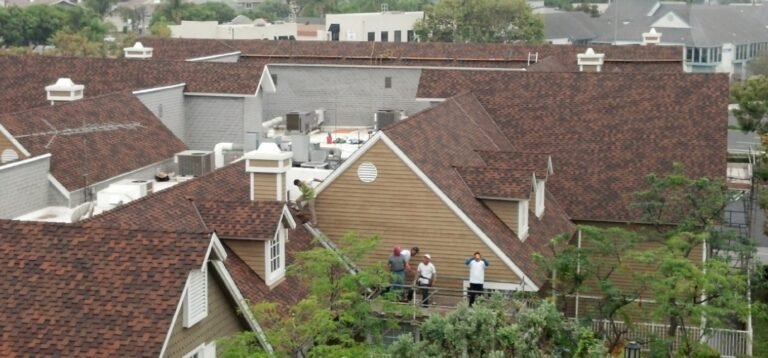 Workers on brown shingle roof, Southern California project.